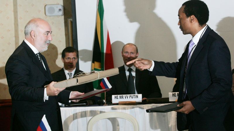 Руският президент Владимир Путин (третият вляво), руският олигарх Виктор Векселберг (вляво) и тогавашният руски министър на природните ресурси Юрий Трутнев (вторият вляво) присъстват на южноафриканско-руски бизнес форум в Кейптаун, Южна Африка през септември 2006 г.  
